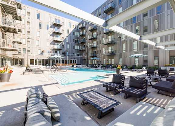 A large outdoor pool area with lounge chairs and umbrellas.