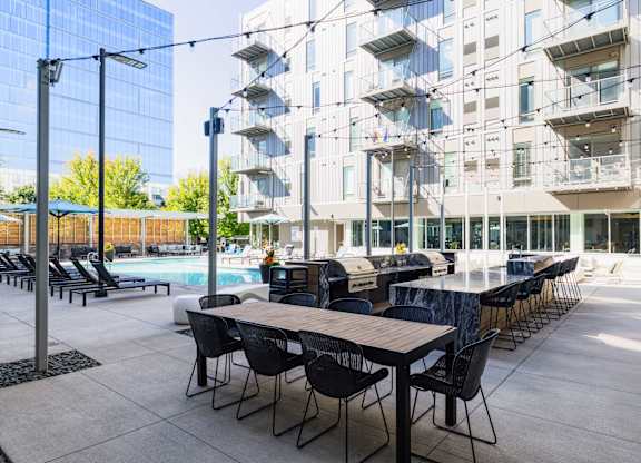 A modern outdoor dining area with tables and chairs is set up in front of a contemporary building.