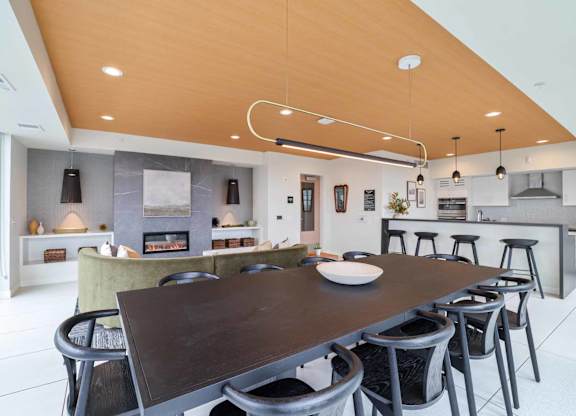 A modern kitchen with a wooden ceiling and a dining table with chairs.