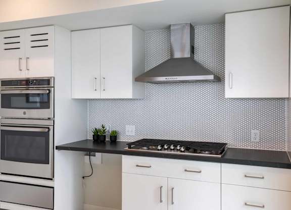A modern kitchen with white cabinets and a black countertop.