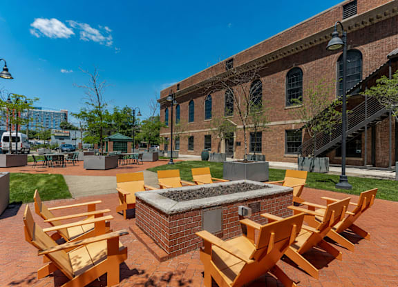 A fire pit surrounded by wooden chairs in a courtyard.