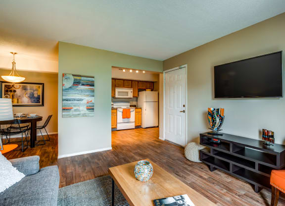 a living room with a tv and a kitchen in the background