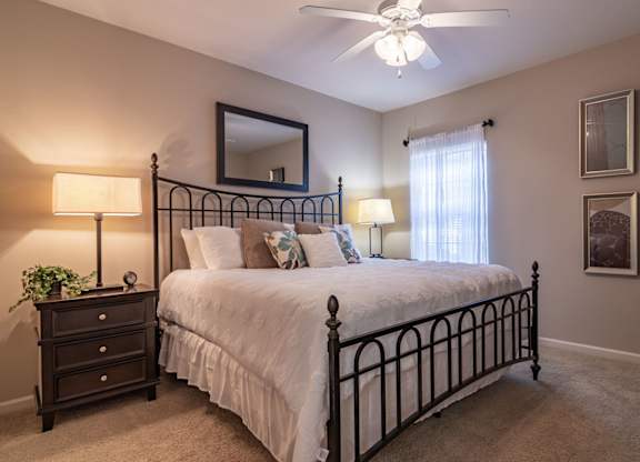 Pet-Friendly Apartments in Opelika, AL – The Crossings of Opelika - a bedroom with a bed and a ceiling fan and