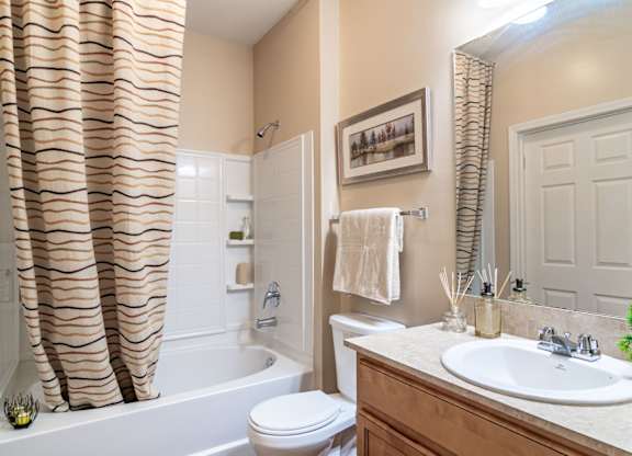 Opelika, AL Apartments – The Crossings of Opelika - a bathroom with a white toilet next to a white bathtub