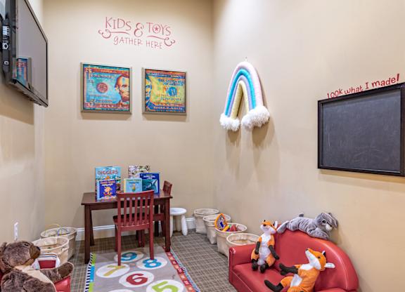 Pet-Friendly Apartments in Opelika, AL – The Crossings of Opelika -  a childs play area with toys and a chalkboard on the wall