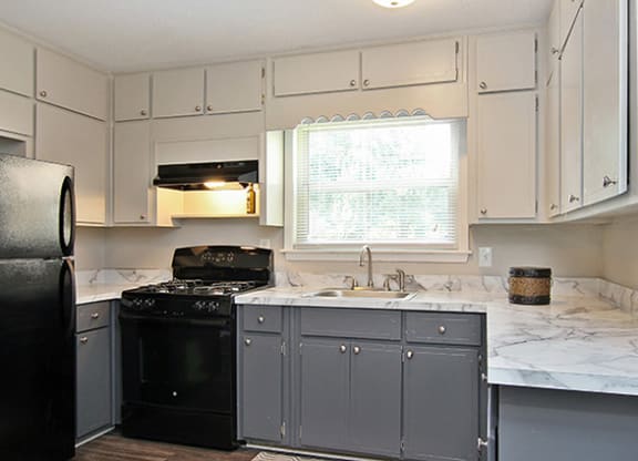 Pet-Friendly Apartments in Atlanta, GA – Estuary – photo of kitchen with white and grey cabinets and black appliances