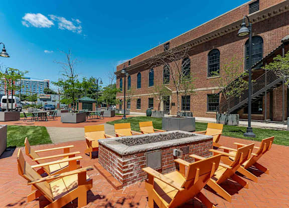 A fire pit surrounded by wooden chairs in a courtyard.