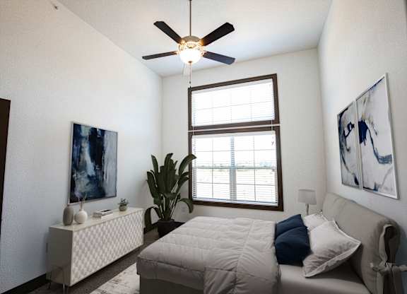 A bedroom with a bed, a ceiling fan, and a window.