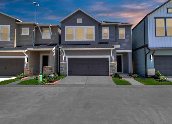 a house with a long driveway and a blue sky in the background