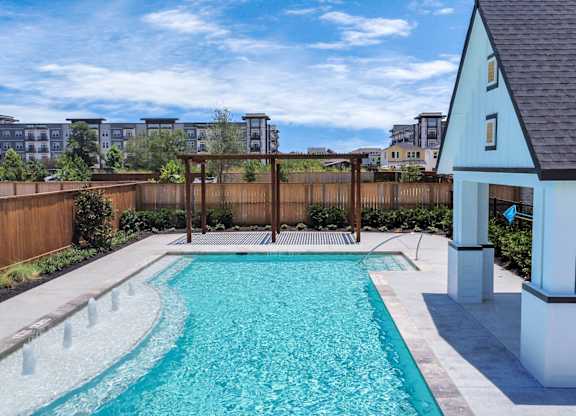 Heights, Houston, TX, Homes For Rent with In-Unit Washer and Dryer - The Crossing at Timbergrove - Swimming Pool with Fountains, a Shaded Area Surrounded by a Wood Fence.
