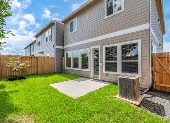 the back of a house with a yard and an air conditioner
