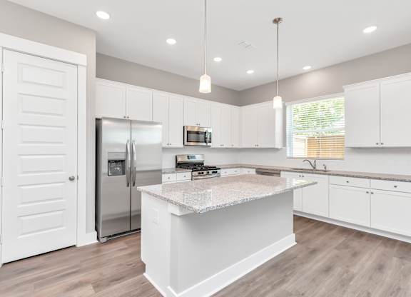 a kitchen with white cabinets and a large island with granite countertops