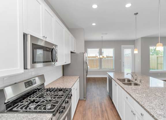 Heights, Houston, TX, Homes For Rent - The Crossing at Timbergrove - Kitchen with Stainless Steel Appliances, Hardwood Inspired Flooring, Granite Countertops, and a Kitchen Island.