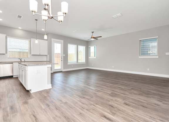 a kitchen and living room with hardwood floors and a chandelier