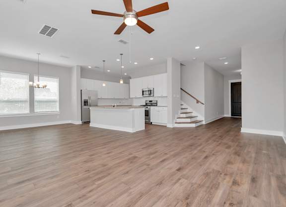 Dog-Friendly homes for rent in Heights, Houston TX - The Crossing at Timbergrove - Open-Concept, Empty Living Space with Hanging Lights, a Ceiling Fan, Windows, Hardwood-Inspired Flooring, and a View 