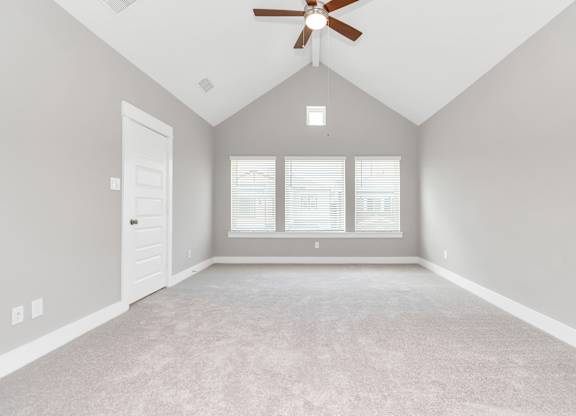 an empty bedroom with a ceiling fan and three windows