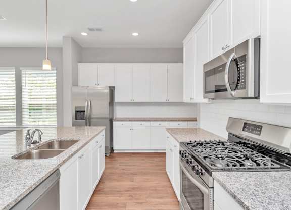 Heights, Houston TX Rental Homes - The Crossing at Timbergrove - Modern Kitchen with Granite Countertops, Stainless Steel Appliances, Expansive White Cabinetry, Hanging Lights, Dual Sink, Nearby Windo
