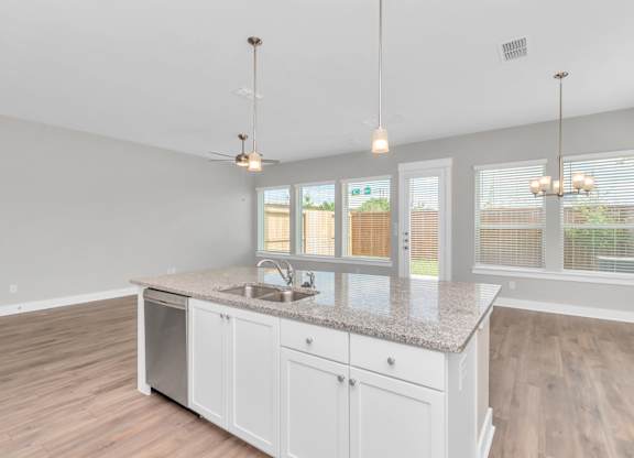 a kitchen with white cabinets and a large island with a sink and a dishwasher