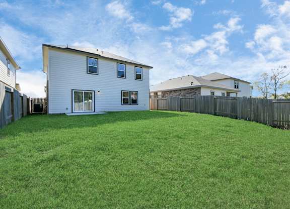 Houston, TX Single-Family Homes for Rent - Imperial Forest - A Backyard with a Small Concrete Patio, Green Lawn Enclosed by a Wooden Privacy Fence.