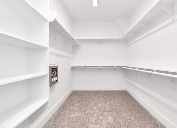 a walk in closet with white walls and white shelves