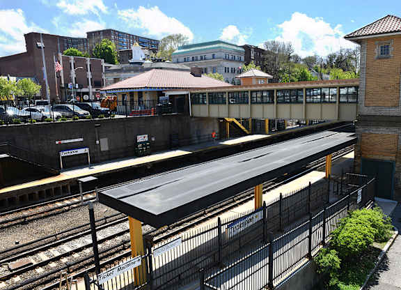 A train station with a black roof and a yellow fence.