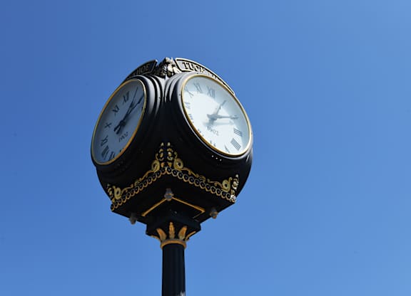 A clock tower with two clocks on top of a black pole.