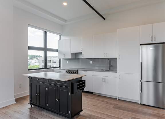 A modern kitchen with white cabinets and a black island.