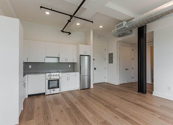 A kitchen with white cabinets and a wooden floor.