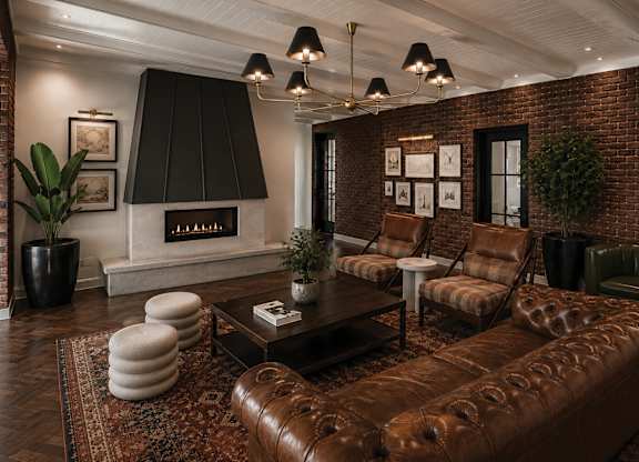 A living room with a brown leather couch and a fireplace.