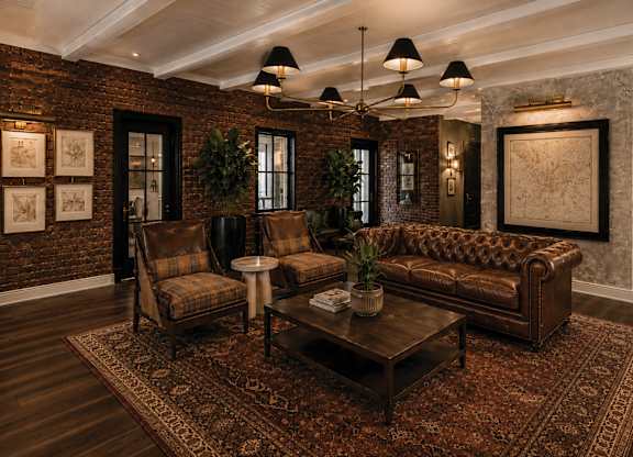 A living room with a brown leather couch, a brown coffee table, and a rug.