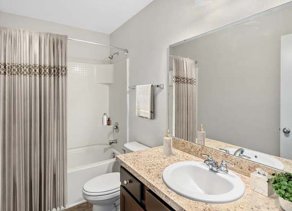 A bathroom with a toilet, sink, and shower curtain.