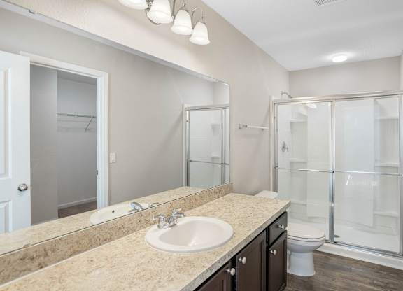 A bathroom with a sink, mirror, and shower.