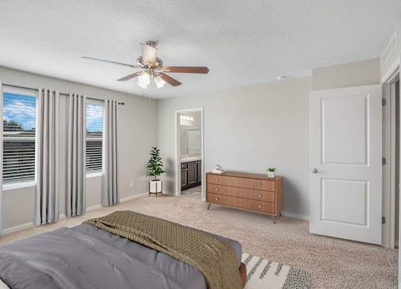 A bedroom with a bed, dresser, and sliding glass doors.