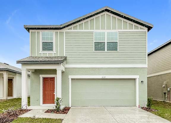 A two-story house with a garage door and a brown door.