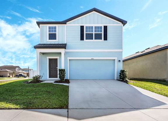 A two-story house with a garage and a driveway.