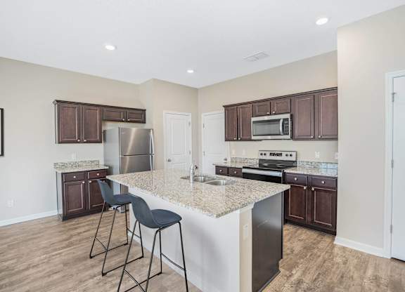 A kitchen with a white island and dark brown cabinets.