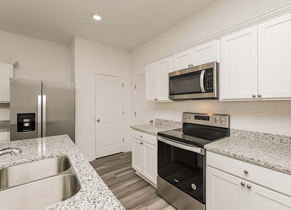 A kitchen with a stainless steel refrigerator, microwave, oven, and sink.