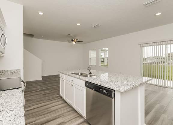 A modern kitchen with a stainless steel dishwasher and a ceiling fan.
