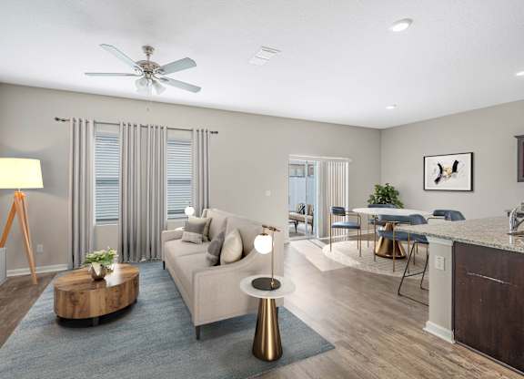 A modern living room with a grey sofa, a wooden coffee table, and a ceiling fan.
