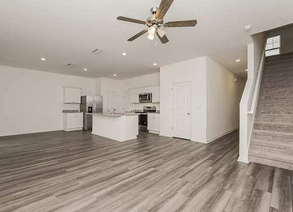 A spacious room with a ceiling fan and wooden flooring.