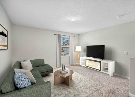 A living room with a green couch, a coffee table, and a television.