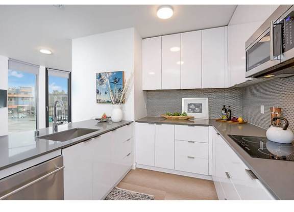 Fremont Apartments for Rent - Inspire Fremont - Kitchen with Stainless Steel Appliances, Granite Countertops, White Cabinets, and Hardwood Style Flooring