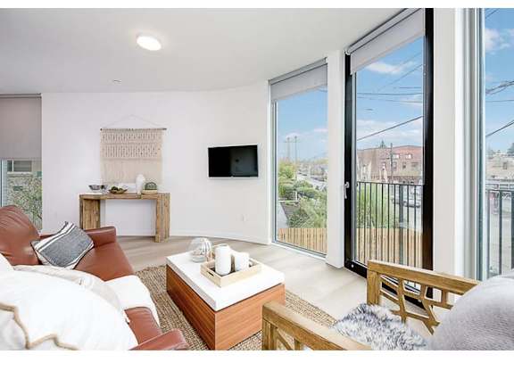 Apartments In Seattle, WA For Rent - Inspire Fremont - Living Room With Floor-To-Ceiling Windows, Hardwood-Style Flooring, And A Large Sofa.