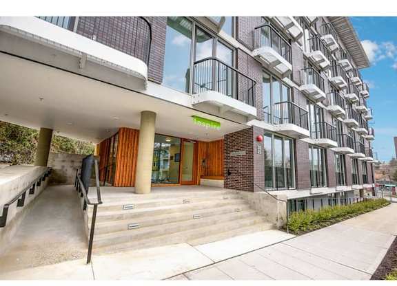Fremont, WA Apartments For Rent - Inspire Fremont - Streetview Of The Building, Large Glass Windows, Wheelchair Ramp, Paved Side Walk, And White Balconies.