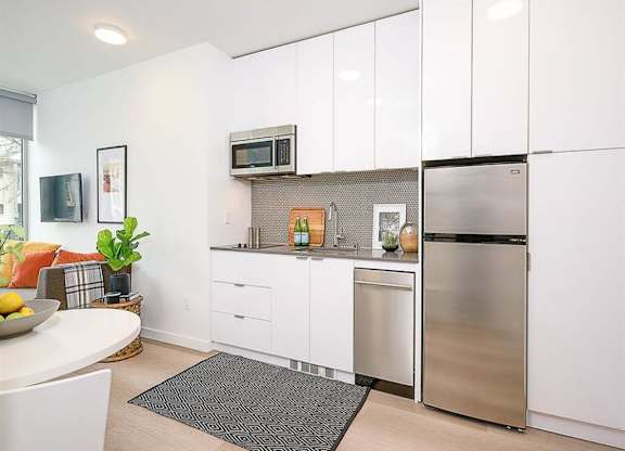 Apartments In Seattle, WA - Inspire Fremont - Kitchen With Granite-Style Countertops, Large Cabinets, And Modern Appliances.