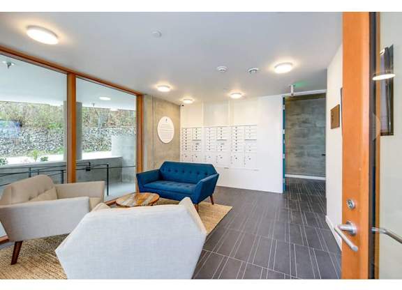 Apartments Fremont, WA - Inspire Fremont - Lobby With Mail Boxes, Coffee Table, Lounge Seating, Natural Fiber Rug, And Modern Lighting.