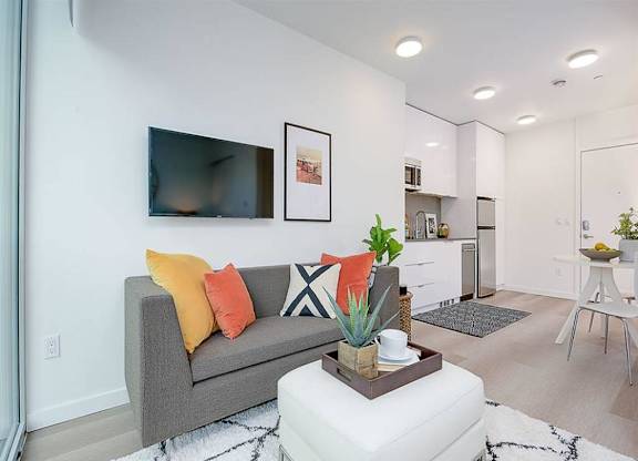 Apartments for Rent in Fremont, WA - Inspire Fremont - Living Room with Wood-Style Floors, Natural Lighting, and a White Ottoman