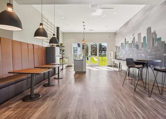 Resident lounge at Willowstone Apartments in Southeast Denver with table seating, wood-style floors, and natural light for gatherings and workspaces