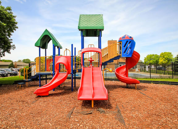 a playground with a red slide and a yellow and blue slide
