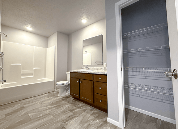 A bathroom with a walk in shower, toilet, sink and a large mirror.
